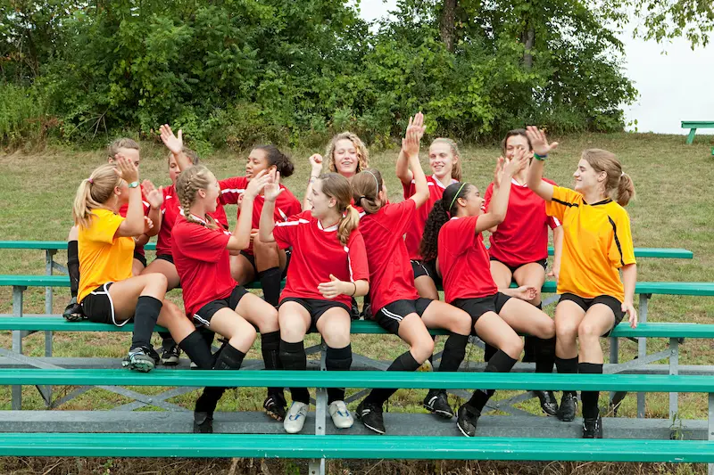 A female soccer team smiling and celebrating together, an example of positive team culture.
