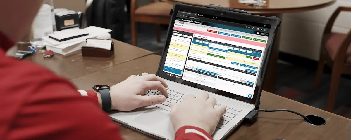 An AD works on his laptop at his desk, avoiding Athletic Director burnout.