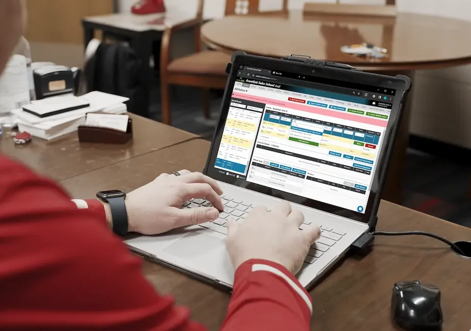 An AD works on his laptop at his desk, avoiding Athletic Director burnout.